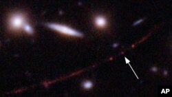 This image made available by NASA on Wednesday, March 30, 2022, shows the star Earendel, indicated by arrow, and the Sunrise Arc galaxy, stretching from lower left to upper right. 