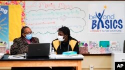 Siswa Quandallis Perry-Fisher (kanan) bersama Tina Walker dalam sesi literasi "Beyond Basics" di SMA Denby, Detroit, Rabu, 27 Oktober 2021. (AP/Paul Sansya)