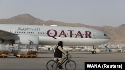 FILE - A Taliban soldier patrols on a bike in front of a Qatar Airways flight at the international airport in Kabul, Afghanistan, September 10, 2021. 