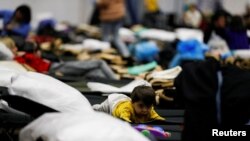 FILE - A child fleeing the Russian invasion of Ukraine lies on a bed inside a school that has been converted to provide shelter, in Przemysl, Poland Feb. 28, 2022.