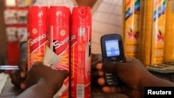 Un client tient son téléphone portable alors qu'il s'apprête à payer des sprays anti-moustiques au marché de Makola, à Accra, au Ghana, le 26 mars 2022.