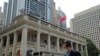 Seorang pria yang mengenakan masker tampak berjalan melewati gedung pengadilan di Hong Kong, pada 30 Maret 2022. (Foto: AP/Kin Cheung)