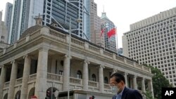 Seorang pria yang mengenakan masker tampak berjalan melewati gedung pengadilan di Hong Kong, pada 30 Maret 2022. (Foto: AP/Kin Cheung)