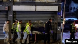 Israeli medical personnel and rescue workers evacuate a dead body from the scene of an attack in which people were killed by gunmen on a main street in Hadera, Israel, March 27, 2022. 