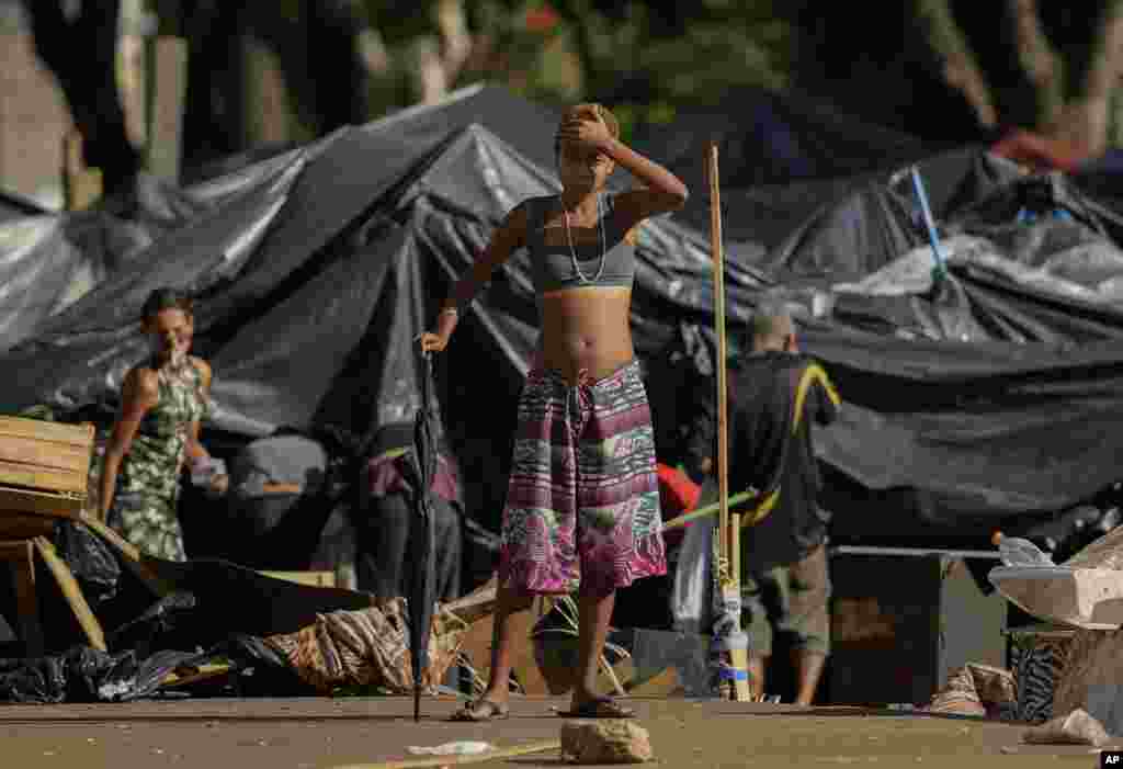 A young homeless woman watches an operation to remove trash and tents used by homeless people and drug users from Princesa Isabel square in downtown Sao Paulo, Brazil.