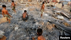 FILE - Boys search for useful items among the ashes of burnt houses after fire destroyed shelters at a camp for internally displaced Rohingya Muslims in the western Rakhine State near Sittwe, Myanmar, May 3, 2016. 