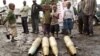 Congolese citizens look at tank shells lying next to roadside, left behind by retreating government troops as they fled assault by M23 rebels, in eastern Congo, Nov. 21, 2012.