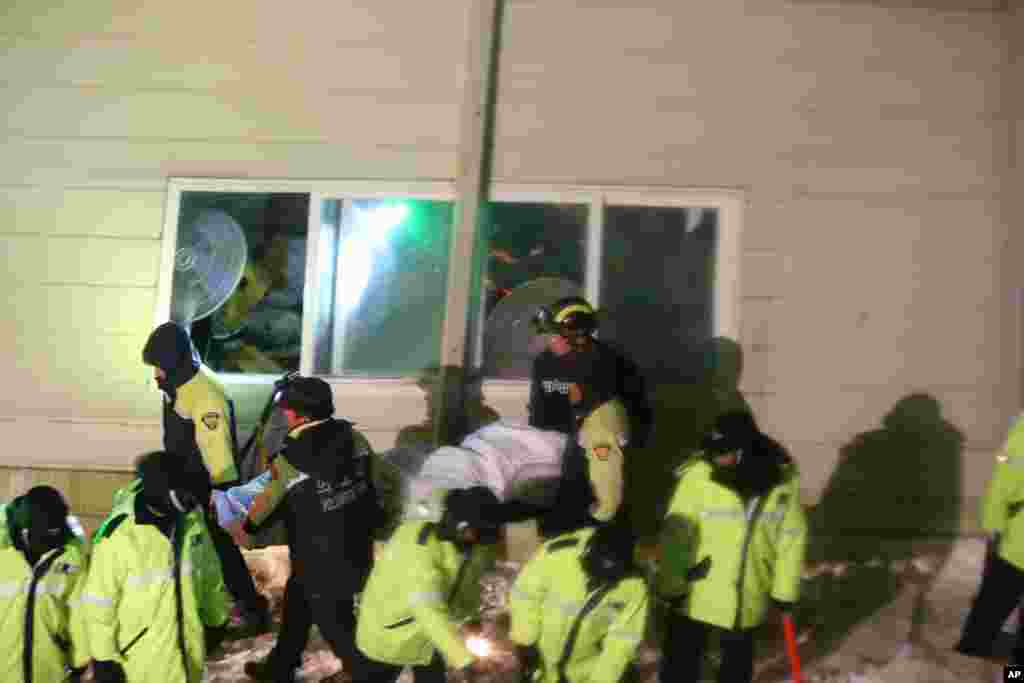 Rescue workers carry a body from a collapsed building in Gyeongju, South Korea, Feb. 17, 2014. 