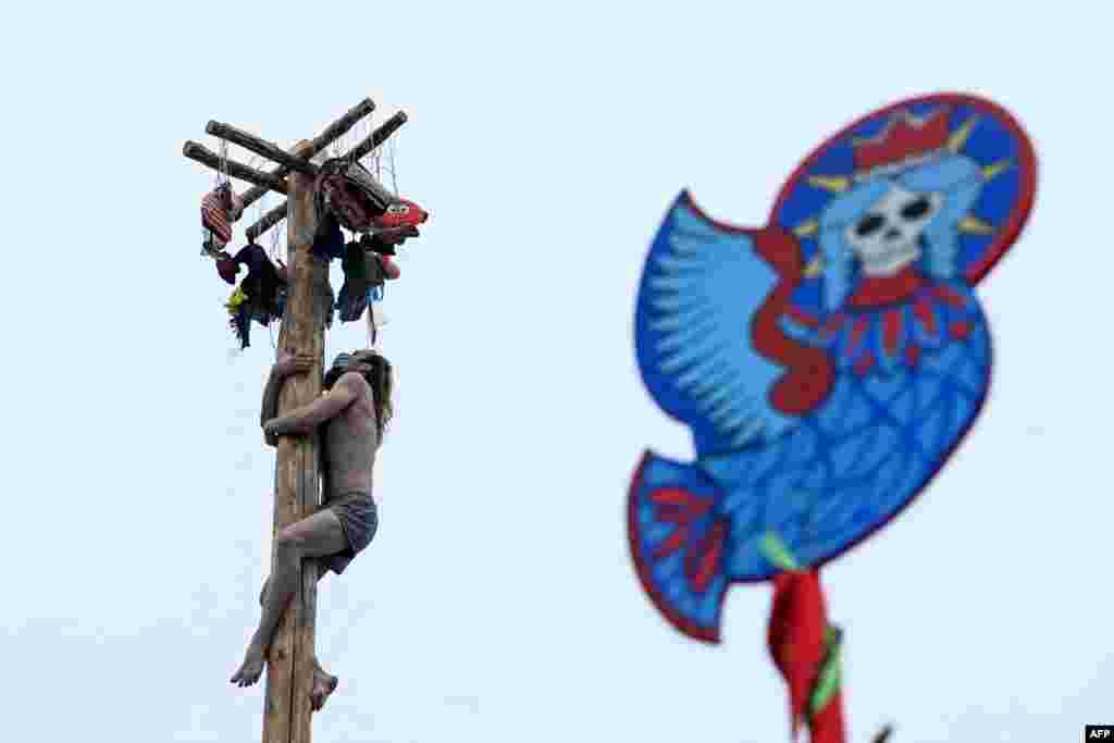 A man wearing a protective mask competes in the pole-climb game as he celebrates the Maslenitsa or Shrovetide, a farewell ceremony to winter close to village of Gzhel about 60 km from Moscow, Russia.