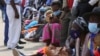 FILE: A woman reads messages on her mobile phone while waiting in a bank queue in Harare, Zimbabwe on Monday, Dec. 13, 2021. In Zimbabwe and other African nations, the virus's resurgence is threatening the very survival of millions of people