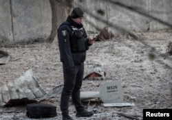 A police officer stands near parts of the drone at the site of a building destroyed by a Russian drone attack, as their attack on Ukraine continues, in Kyiv, Ukraine December 14, 2022. The inscription reads "For Ryazan". (REUTERS/Gleb Garanich)