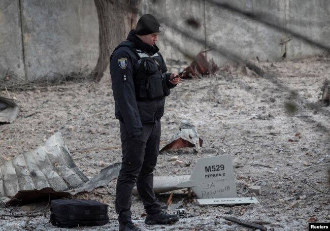 A police officer stands near parts of the drone at the site of a building destroyed by a Russian drone attack, as their attack on Ukraine continues, in Kyiv, Ukraine December 14, 2022. The inscription reads "For Ryazan". (REUTERS/Gleb Garanich)