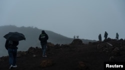 People walk up the hill hoping to see the view of the Mauna Loa volcano eruption during cloudy weather in Hawaii, Dec. 2, 2022. 