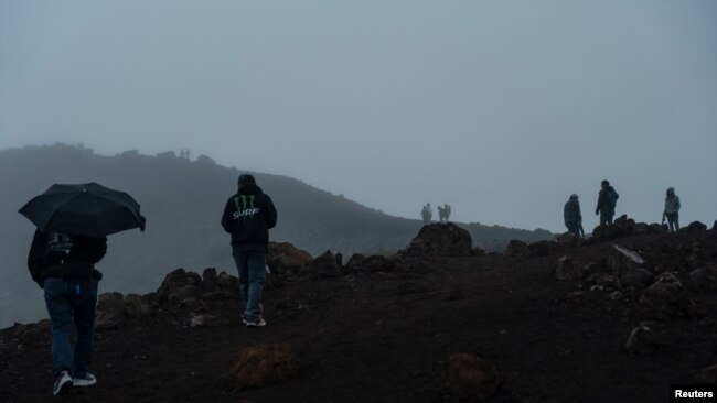 People walk up the hill hoping to see the view of the Mauna Loa volcano eruption during cloudy weather in Hawaii, Dec. 2, 2022.