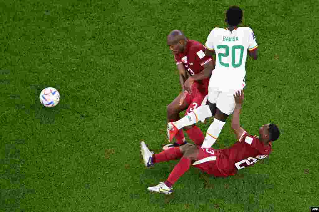 Attaquant ya Sénégal #20 Bamba Dieng (C) azali kowelela ndembo na défenseur #03 Karim Hassan Abdel (G) na milieu #25 Assim<adibo, banso ya Qatar, na match ya Mondial Qatar 2022 na stade Al-Thumama, Doha, 25 novembre 2022. (Photo Kirill KUDRYAVTSEV / AFP)