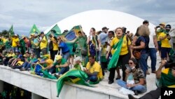 Para pendukung mantan presiden Brazil Jair Bolsonaro berdiri di atap gedung Kongres Nasional setelah mereka melakukan penyerbuan di Brasilia, Brazil, 8 Januari 2023. (Foto: AP)