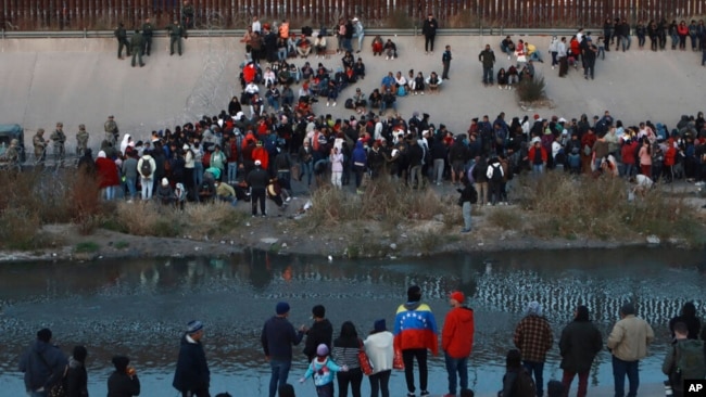 FILE - Migrants gather at a crossing into El Paso, Texas, as seen from Ciudad Juarez, Mexico, Dec. 20, 2022. (AP Photo/Christian Chavez, File)