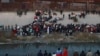 FILE - Migrants gather at a crossing into El Paso, Texas, as seen from Ciudad Juarez, Mexico, Dec. 20, 2022. 