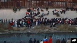 FILE - Migrants gather at a crossing into El Paso, Texas, as seen from Ciudad Juarez, Mexico, Dec. 20, 2022.