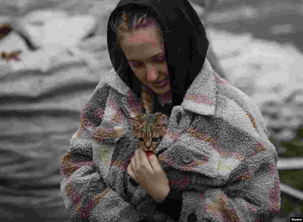 A local resident carries a kitten found in her flat in a residential building destroyed by a Russian missile attack, in the town of Vyshhorod, near Kyiv, Ukraine.
