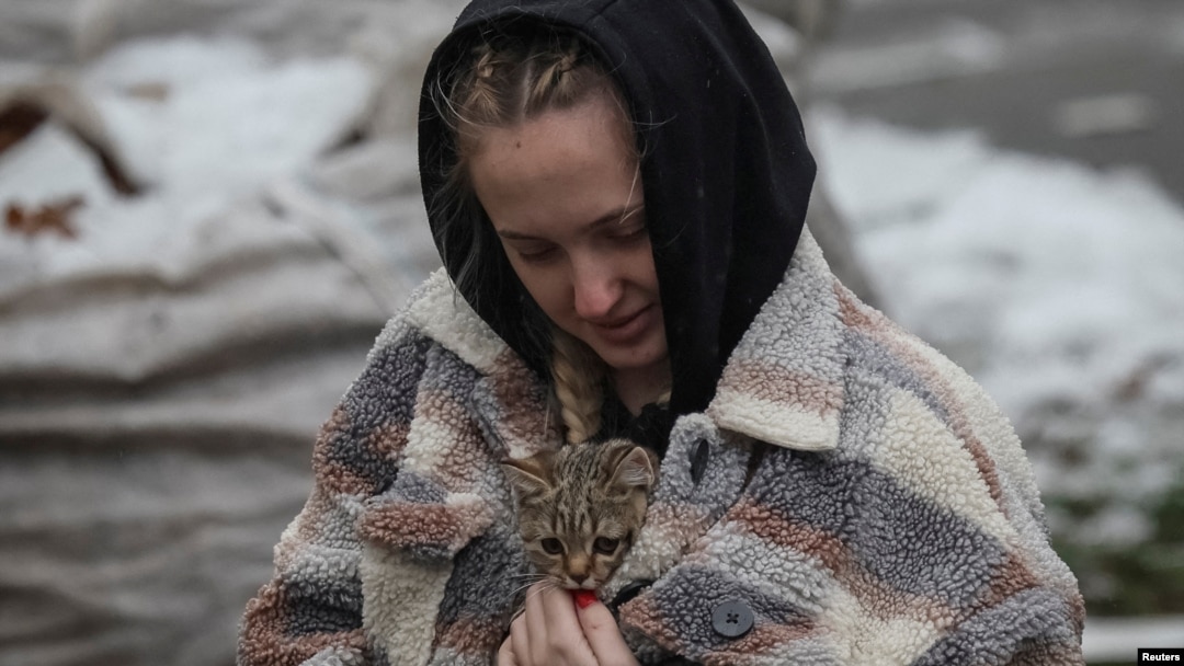 Stanovnica sela Višorod, pored Kijeva, nosi mačku pronađenu u zgradi uništenoj u ruskom napadu (Foto: REUTERS/Gleb Garanich)