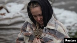 Stanovnica sela Višorod, pored Kijeva, nosi mačku pronađenu u zgradi uništenoj u ruskom napadu (Foto: REUTERS/Gleb Garanich)