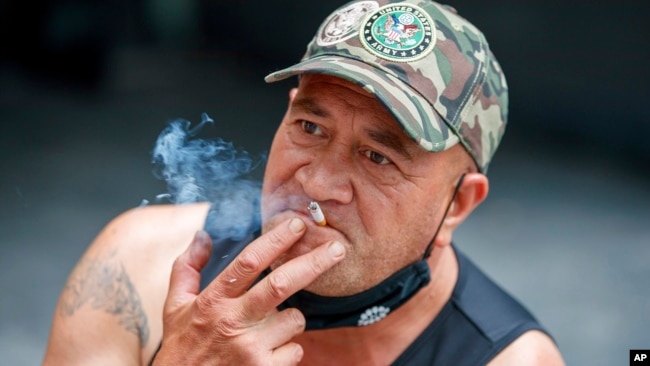 FILE - A man sits while smoking in Auckland, New Zealand, Thursday, Dec. 9, 2021. New Zealand on Tuesday passed into law a unique plan to phase out tobacco smoking by imposing a lifetime ban on young people buying cigarettes. (AP Photo/David Rowland, File)