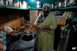 Bilal Sufi, owner of Baking Virsa eatery, prepares kebabs in Lahore, Pakistan, Saturday, Dec. 3, 2022. (AP Photo/K. M. Chaudary)