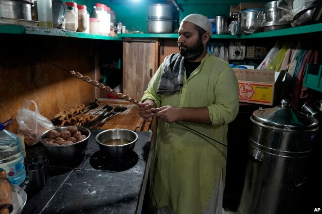 Bilal Sufi, owner of Baking Virsa eatery, prepares kebabs in Lahore, Pakistan, Saturday, Dec. 3, 2022. (AP Photo/K. M. Chaudary)