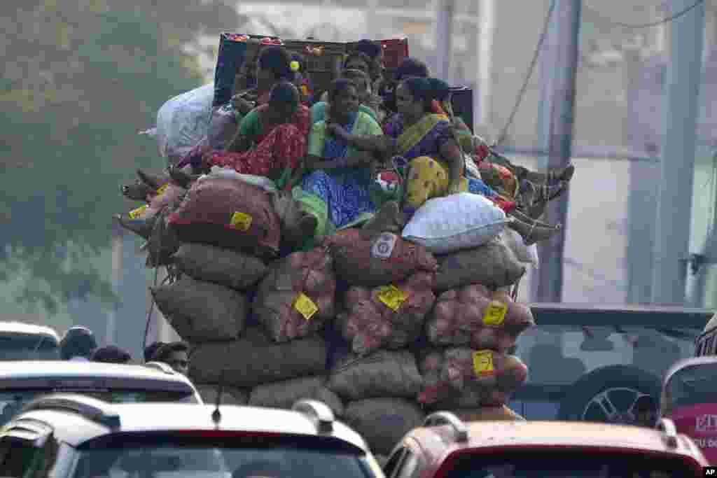 Vendors sit on top of a small truck with sacks of vegetables and travel to a market in Hyderabad, India.