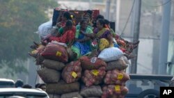 Vendors sit atop a mini truck with sacks of vegetables and travel to a market in Hyderabad, India.
