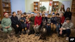 Children traumatized by the war pose for photo with an American Pit Bull Terrier "Bice" in the Center for Social and Psychological Rehabilitation in Boyarka close Kyiv, Ukraine, Wednesday, Dec. 7, 2022. (AP Photo/Vasilisa Stepanenko)