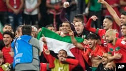 Morocco's players hold the Palestinian flag after defeating Spain in the World Cup in Al Rayyan, Qatar, Dec. 6, 2022.