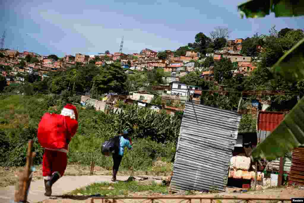 Човек облечен како Дедо Мраз дели играчки на деца во населба со ниски приходи, во Каракас, Венецуела.