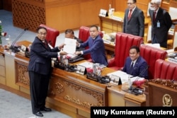 Bambang Wuryanto, head of the parliamentary commission overseeing the revision, passes the report of the new criminal code to Sufmi Dasco Ahmad, Deputy speaker of the House of Representatives, during a parliamentary plenary meeting in Jakarta, Indonesia, December 6, 2022. REUTERS/Willy Kurniawan