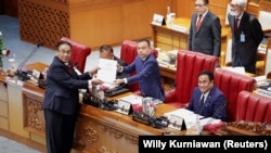 印尼国会负责修法的委员会主席班邦（Banmbang Wuryanto）在雅加达的国会全体会议上将新刑法报告递给众议院副议长。（2022年12月6日）