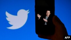 FILE In this file photo taken on October 4, 2022, a phone screen displays a photo of Elon Musk with the Twitter logo shown in the background, in Washington, DC. 