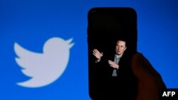 FILE: In this photo taken Oct. 4, 2022, a phone screen displays a photo of Elon Musk with the Twitter logo shown in the background, in Washington, DC