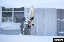 A man clears snow from his roof after a winter storm hit the Buffalo region in Amherst, New York, U.S., December 25, 2022. REUTERS/Brendan McDermid