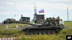 FILE - Recruits listen to an instructor standing atop of a tank during a military training at a firing range in the Rostov-on-Don region in southern Russia, Oct. 4, 2022.