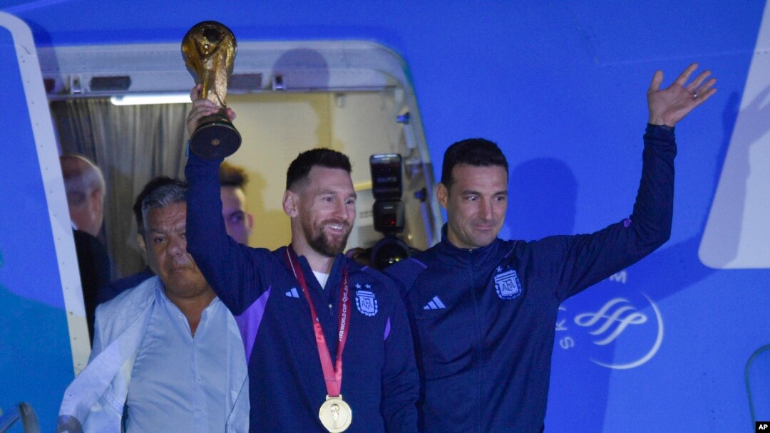 Vedet foutbol Ajantin Lionel Messi kenbe twofe Mondyal Foutbol FIFA a pandan lap desann avyon an ak antrene seleksyon nasyonal la Lionel Scaloni nan Buenos Aires, kapital peyi a, Madi 20 Desanm, 2022. 