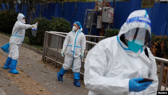 Pandemic prevention workers in protective suits walk outside a locked-down residential compound as COVID-19 outbreaks continue in Beijing, China, Nov. 18, 2022.