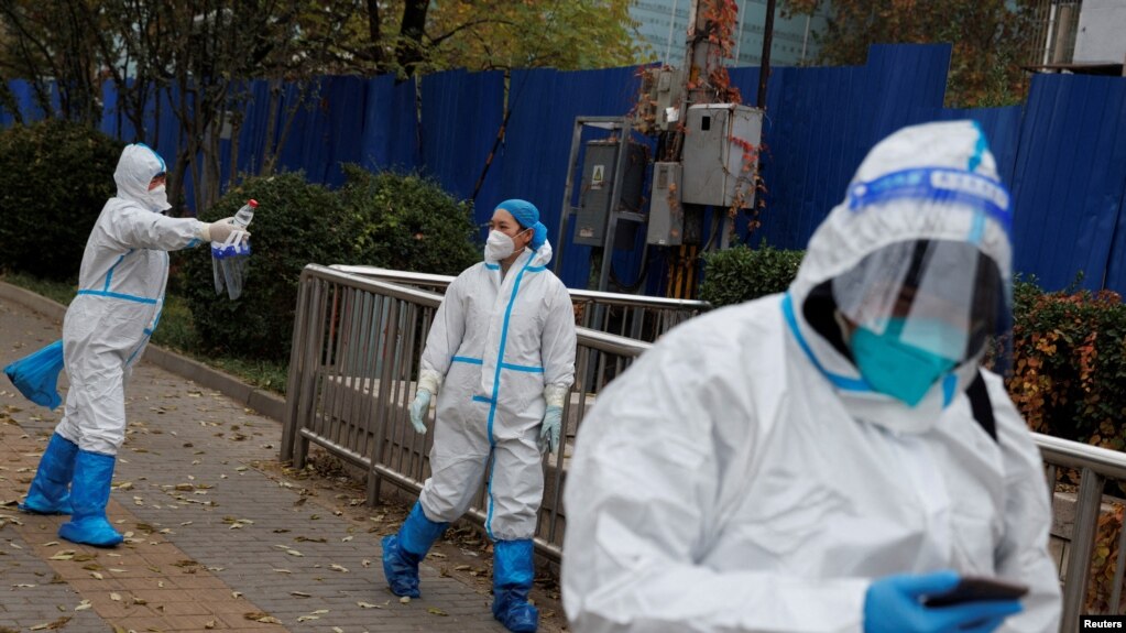 2022年11月18日，随着COVID-19疫情在中国北京继续爆发，身穿防护服的防疫工作人员走出了一个封闭的住宅区。(photo:VOA)