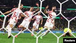 Croatia players celebrate as Brazil's Marquinhos, right, missed a penalty kick to secure the World Cup victory for Croatia on Dec. 9, 2022. 