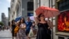 FILE - A woman holds an umbrella to shelter from the sun during a hot sunny day in Madrid, Spain, July 18, 2022. 