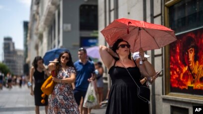 People sheltering from the rain beneath umbrellas walk past a