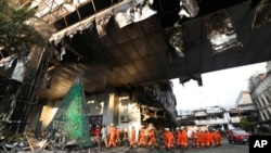 Cambodian and Thai rescue experts walk through a ruined building for a searching operation at the scene of a massive fire at a Cambodian hotel casino in Poipet, west of Phnom Penh, Cambodia, Dec. 30, 2022. 