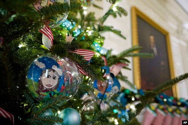 Ornaments containing self-portraits of students from across the country hang from a tree in the State Dining Room of the White House during a press preview of holiday decorations at the White House, Monday, Nov. 28, 2022, in Washington. (AP Photo/Patrick Semansky)