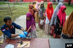 Pengungsi Rohingya mendaftarkan identitasnya ke petugas imigrasi di tempat penampungan sementara di Laweueng, Aceh 29 Desember 2022. (Foto: AFP)