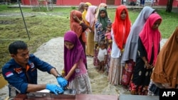 Rohingya refugees register with Indonesian immigration officers at a temporary shelter in Laweueng, Aceh province. 